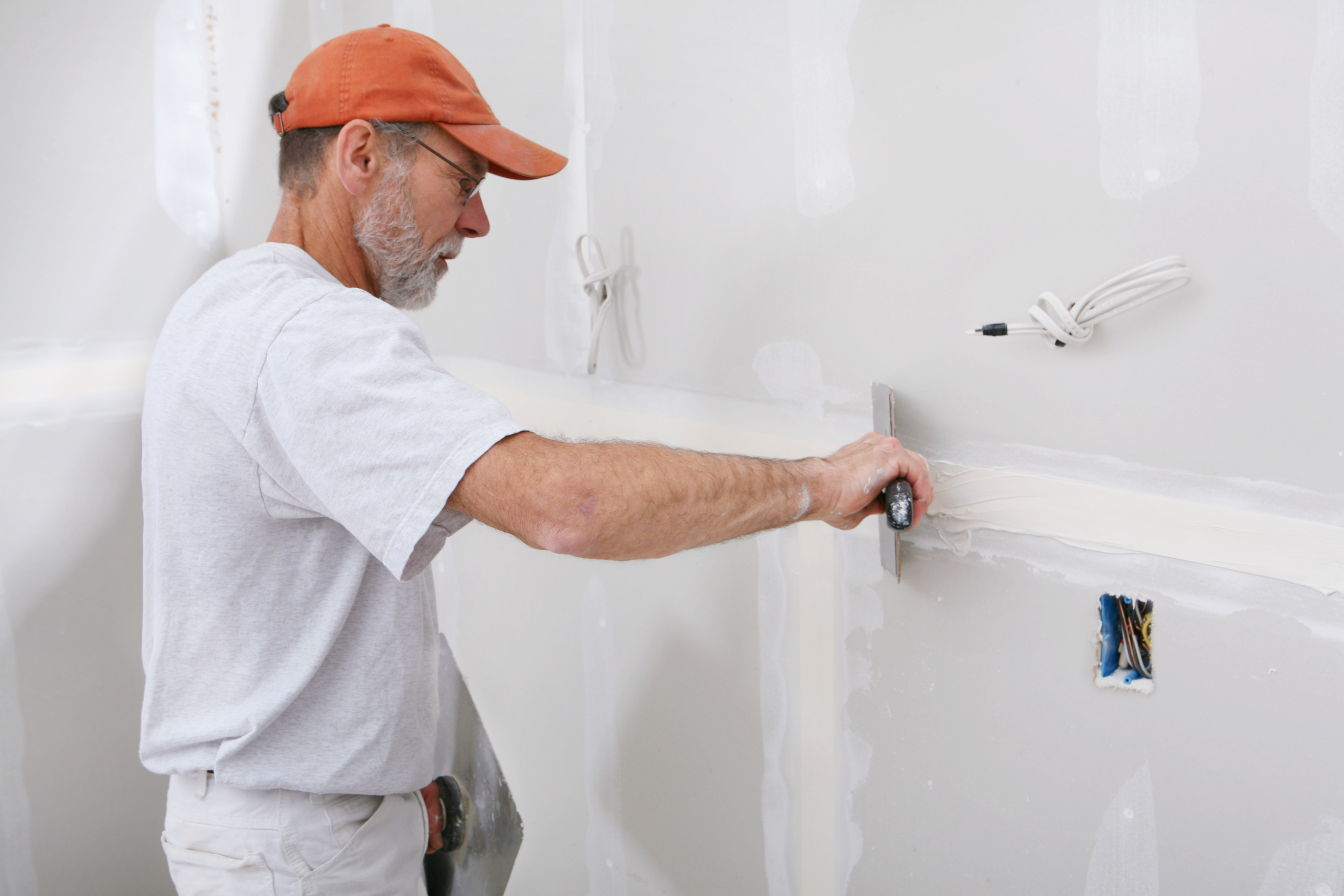 A professional handyman repairing a drywall in a house in Peel